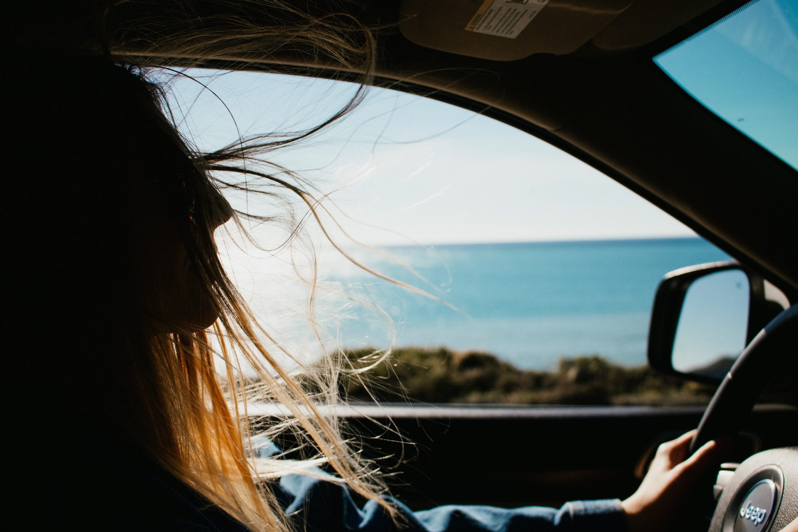 A girl driving by the sea in the car
