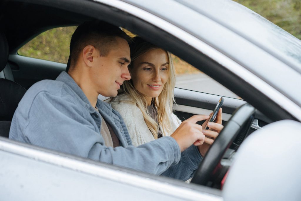 Couple sat in car with mobile phone