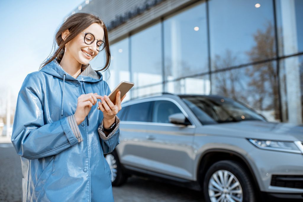 woman stood next to car with mobile phone