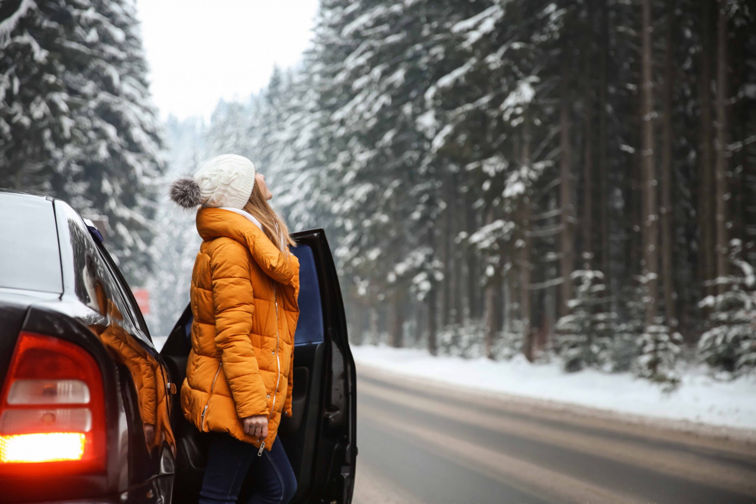 Young woman near car at winter resort