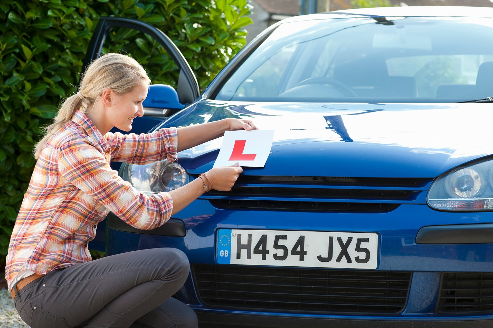 Woman attaching an L Plate to the front of a car before practising using Dayinsure learner driver insurance.